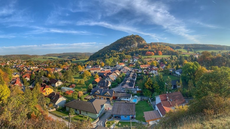 Panoramaansicht von Alland mit dem charakteristischen Hausberg, umgeben von Wäldern und dem historischen Ortskern